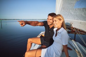 Smiling young couple enjoying the sea views while out sailing